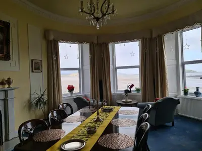 a dining room with a table and chairs and windows at Balcary Bay Country House Hotel in Auchencairn