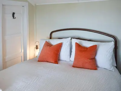 two orange pillows sitting on a white bed at Ludlow Bank in Coulderton