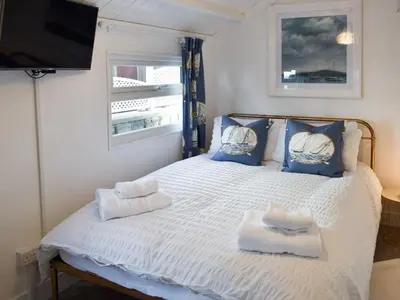 a bedroom with a white bed with blue pillows and a television at Ludlow Bank in Coulderton