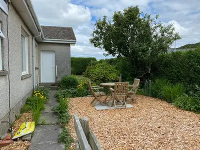 a patio with a table and chairs next to a house at Craignair in Port William