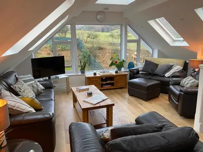 a living room with leather couches and a tv at Latrigg View in Keswick