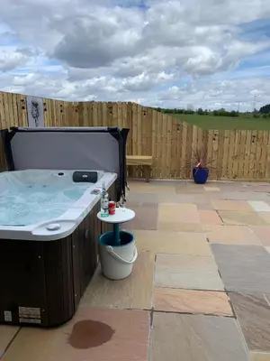 a hot tub on a patio with a wooden fence at Thistle Pod Farm Stay with Hottub Sleeps 2 in Galston