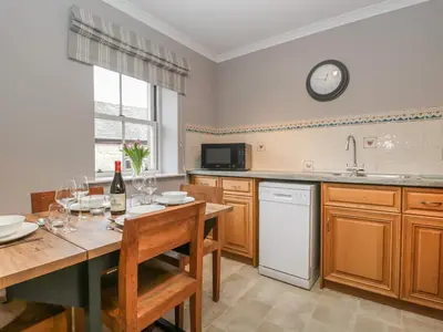 a kitchen with a table and a clock on the wall at The Crook in Penrith