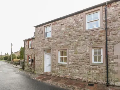 an old brick house with white doors on a street at The Crook in Penrith