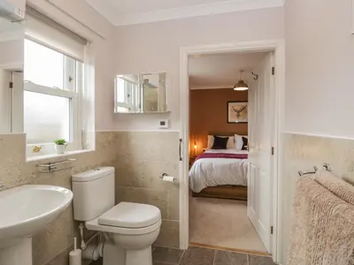 a bathroom with a toilet and a sink and a bed at The Crook in Penrith