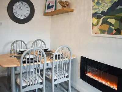 a dining room with a table and a fireplace at Eskin Den in Keswick