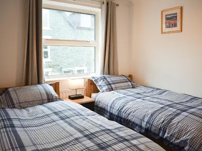 two beds in a room with a window at Eskin Den in Keswick