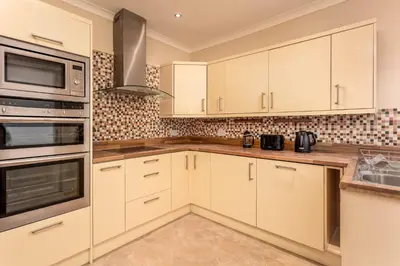 a kitchen with white cabinets and stainless steel appliances at Sunset View - Donnini Apartments in Ayr
