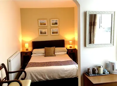 a bedroom with a bed and a mirror on the wall at Melrose Guest House in Douglas