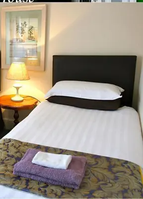 a bedroom with a bed with a pillow and a lamp at Melrose Guest House in Douglas