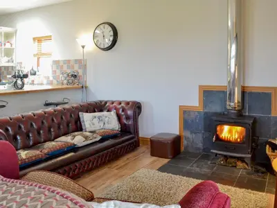 a living room with a leather couch and a fireplace at Laird House in Lochmaben