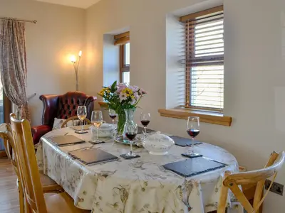 a dining room table with wine glasses and flowers on it at Laird House in Lochmaben