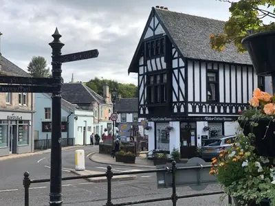 a street sign in front of a black and white building at East Church House, Unique 9 bedroom Church, Historic Market Town. in Strathaven