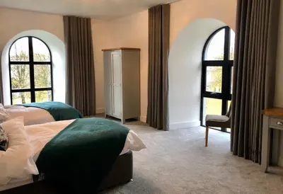 a bedroom with two beds and two windows at East Church House, Unique 9 bedroom Church, Historic Market Town. in Strathaven