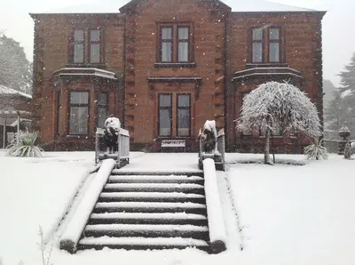 a brick building with snow on the steps at Edenbank Hotel in Dumfries