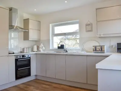 a kitchen with white cabinets and a window at Loanmhor in Kilmory