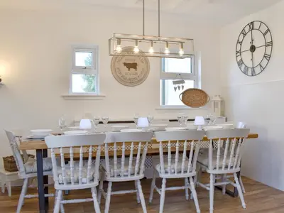 a dining room table with white chairs and a clock at Loanmhor in Kilmory
