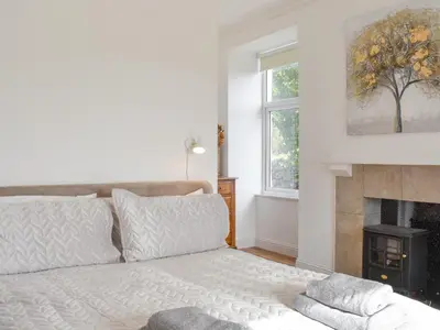 a white bedroom with a bed and a fireplace at Loanmhor in Kilmory
