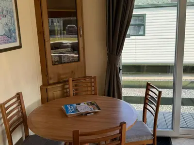 a wooden table and chairs with a book on it at Happydays Caravan 1 Newton Stewart in Bailliewhir