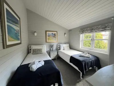 a bedroom with two beds and a window at Holly Blue - Cosy wooden lodge Kippford in Dalbeattie