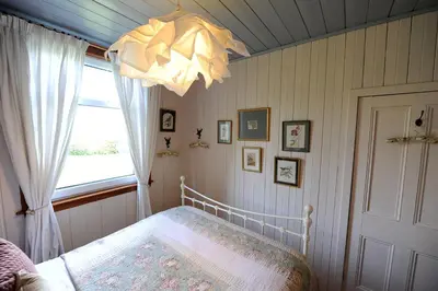 a bedroom with a bed and a window and a chandelier at The Green House at Tathhill in Beattock