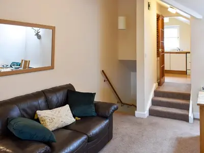 a living room with a leather couch and stairs at Walkers Retreat in Keswick