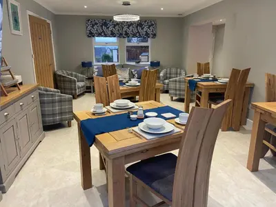 a dining room with wooden tables and chairs at Kirkwirral Bed & Breakfast in Dumfries