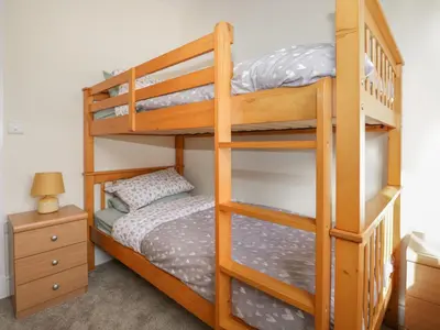 a bedroom with two bunk beds and a night stand at The Croft Bungalow in Wigton