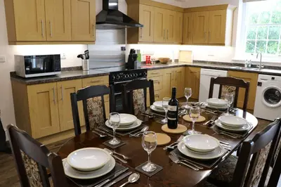 a kitchen with a table with plates and wine glasses at Tallentire Hall in Cockermouth