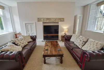 a living room with leather couches and a coffee table at Tallentire Hall in Cockermouth