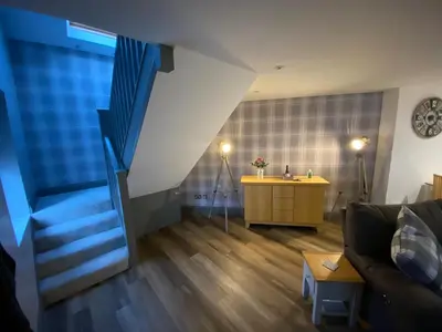 a living room with a staircase and a couch at holidayhomemoffat,com (Stable Cottage) in Moffat