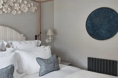 a bedroom with a bed with white sheets and blue pillows at Little Nut Cottage in Ambleside