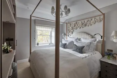 a bedroom with a large white bed with a large mirror at Little Nut Cottage in Ambleside
