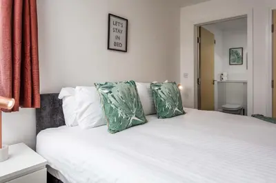 a bedroom with a white bed with green pillows at Walker Suite No52 - Donnini Apartments in Kilmarnock