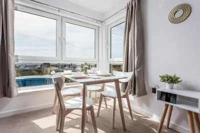 a dining room with a table and chairs in front of a window at Walker Suite No52 - Donnini Apartments in Kilmarnock