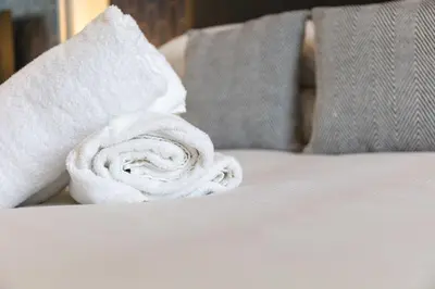 a roll of white towels sitting on a bed at Main Street View - Donnini Apartments in Prestwick