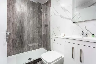 a bathroom with a shower and a toilet and a sink at Main Street View - Donnini Apartments in Prestwick