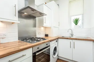 a white kitchen with a stove and a sink at Main Street View - Donnini Apartments in Prestwick