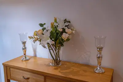 two glasses and a vase of flowers on a dresser at Low Haven in Keswick