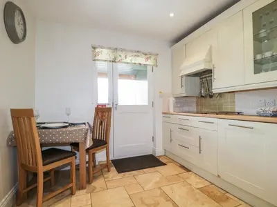 a kitchen with white cabinets and a table with chairs at Glen Cottage in Penrith
