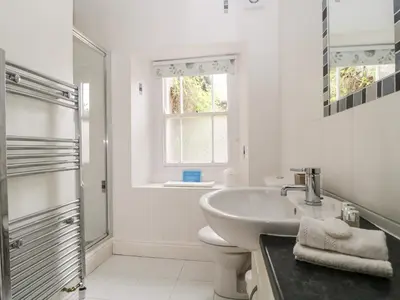 a white bathroom with a sink and a shower at Glen Cottage in Penrith