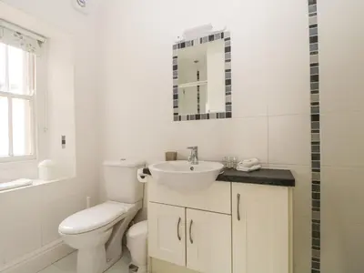 a white bathroom with a toilet and a sink at Glen Cottage in Penrith