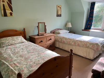 a bedroom with two beds and a mirror and a dresser at The Maid's House in Lanark