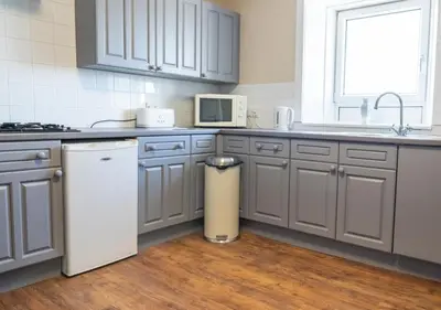 a kitchen with gray cabinets and a white microwave at Apartment 16 in Castle Douglas