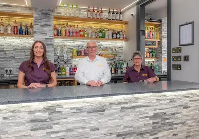 three people standing behind a counter at a bar at Apartment 16 in Castle Douglas