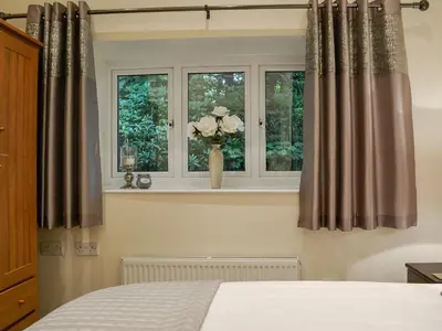 a bedroom with a window with a vase of flowers at The Coach House in Keswick