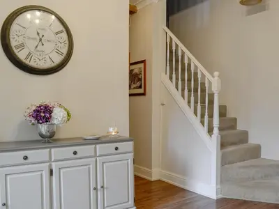 a staircase with a clock on the wall and a white cabinet at The Coach House in Keswick
