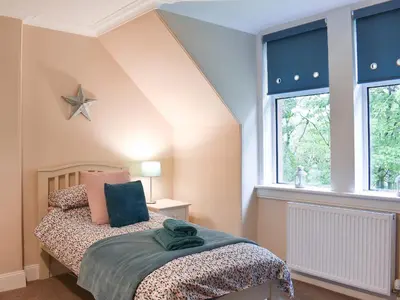 a bedroom with a bed and two windows at Ingleside in Whiting Bay