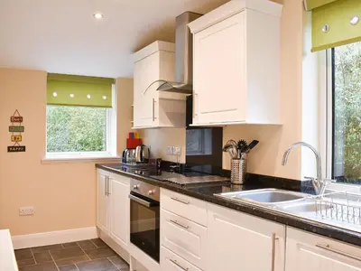 a kitchen with white cabinets and a sink at Ingleside in Whiting Bay