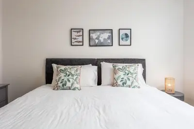 a bedroom with a bed with white sheets and pillows at Walker Suite No54 - Donnini Apartments in Kilmarnock